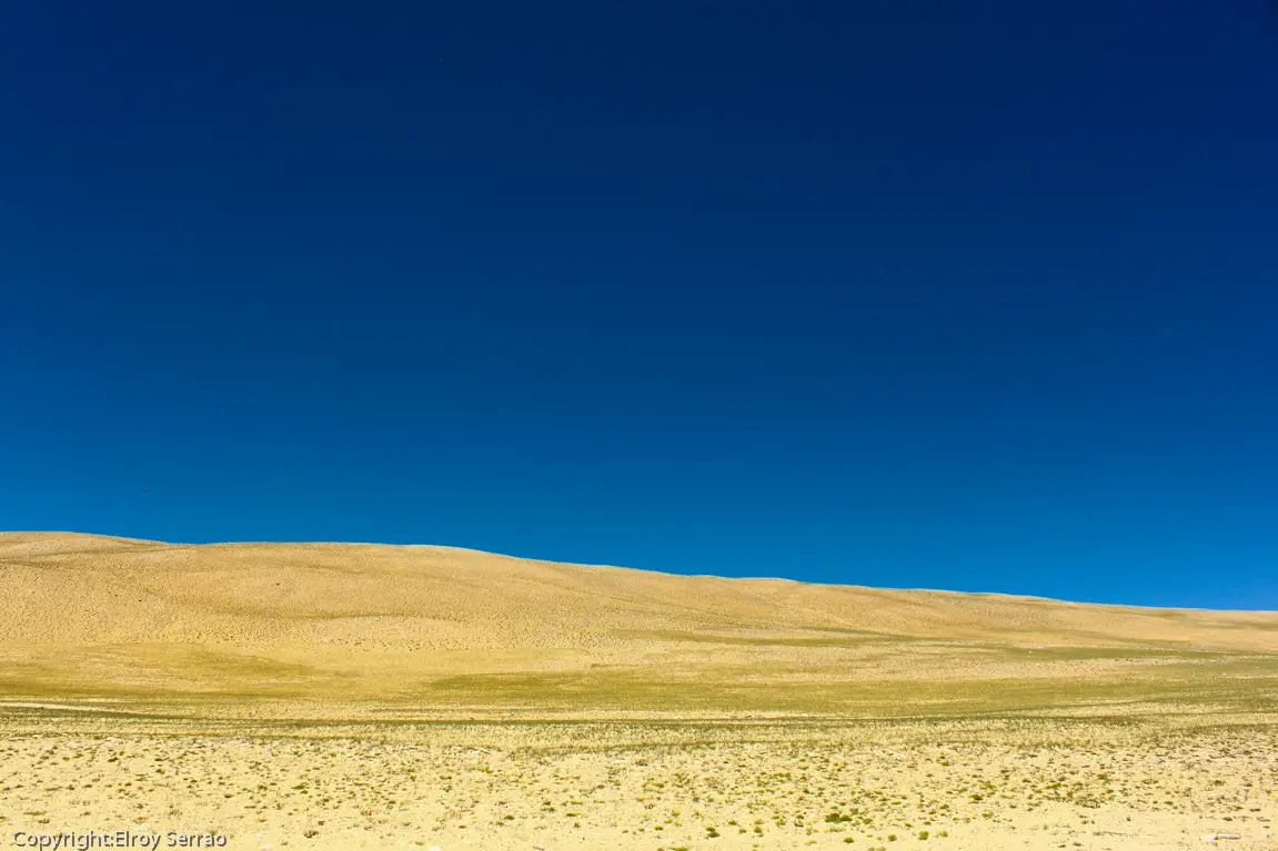 Open high-altitude plateau landscape under a clear blue sky in Changthang