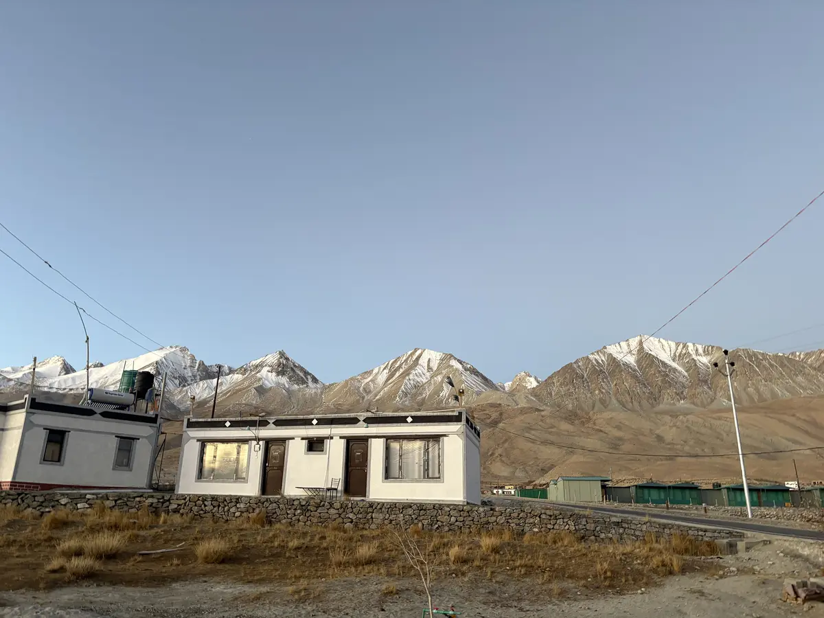 A whitewashed village house with snow-capped mountains behind in Hanle