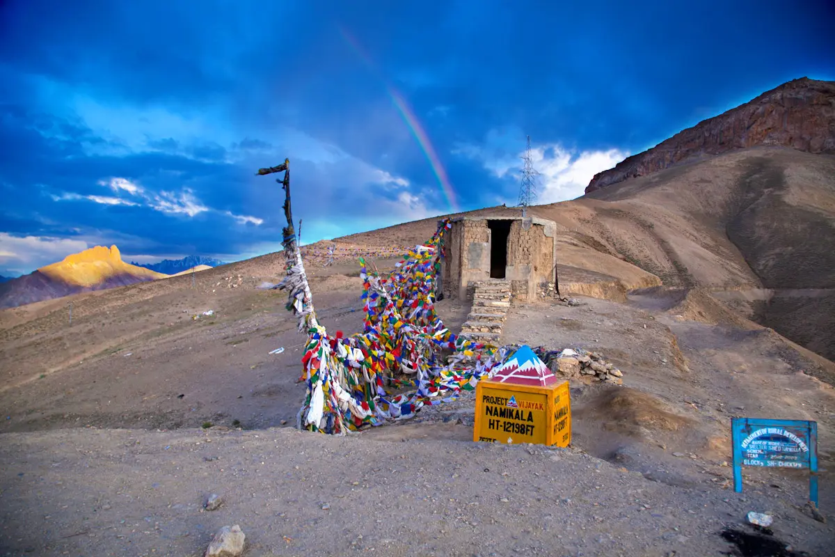 Prayer flags and signboard at Namika La under a blue sky