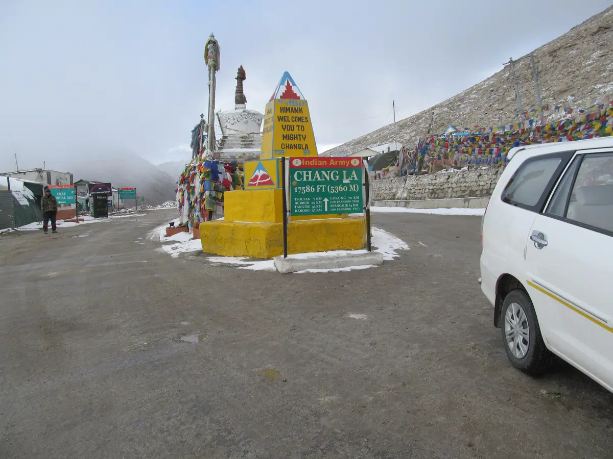 Snow patches and prayer flags at Chang La pass on the road to Pangong