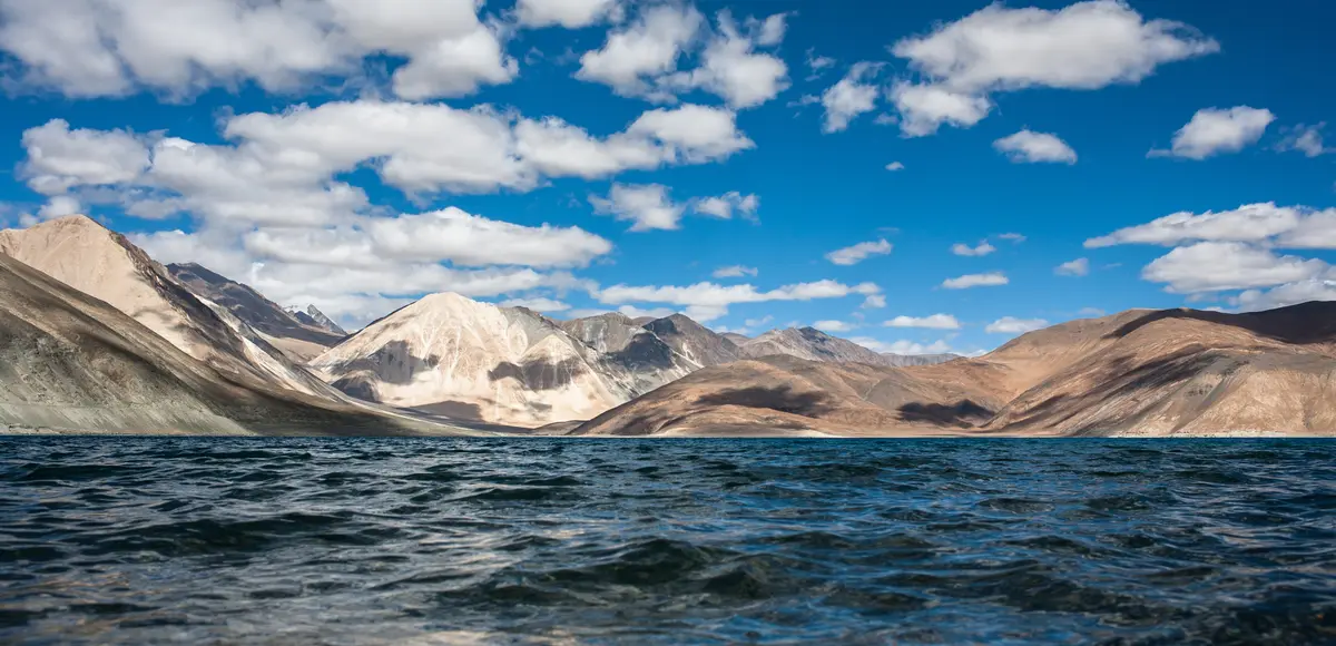 Bright blue water of Pangong Tso with brown mountains behind