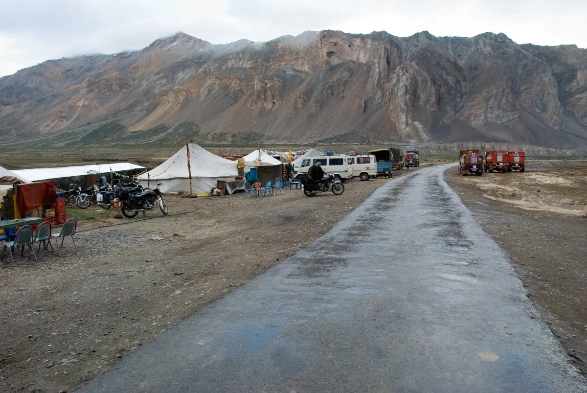 Road passing seasonal tents and parked vehicles at Sarchu