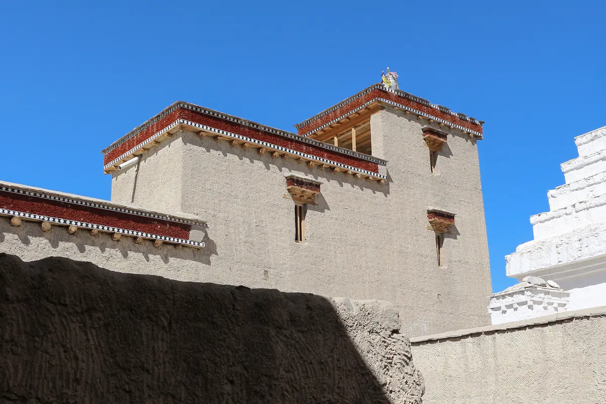 Walls of Shey Palace and a white chorten against a blue sky