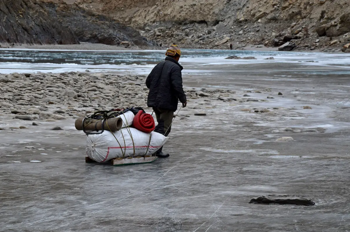 A trekker pulling a sledge across the frozen Zanskar river